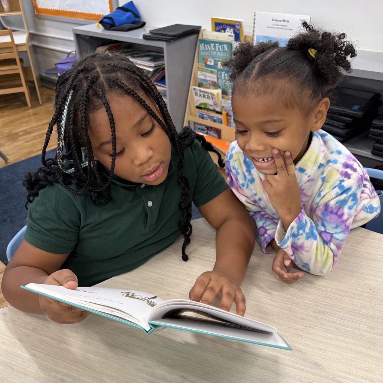 Early Literacy in Action at McDaniel School Two young students sit together at a table reading a book, practicing early literacy skills in a classroom at McDaniel School.