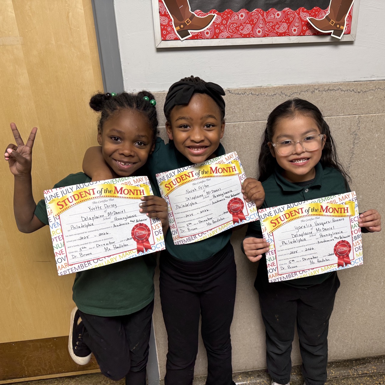 Student of the Month Honorees at McDaniel School Three elementary students smile while holding Student of the Month certificates in a school hallway at McDaniel School.